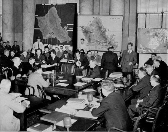 Una de las sesiones del Congreso realizadas para investigar qué pasó en Pearl Habor el 7 de diciembre de 1941. En la pared del fondo están desplegados varios mapas de la isla de Oahu