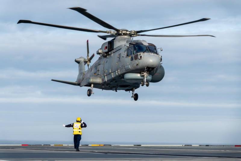 Personal de cubierta dirige la toma en el “Prince of Wales” de un helicóptero Leonardo “Merlin” de su versión “Crowsnest”. Personal de cubierta dirige la toma en el “Prince of Wales” de un helicóptero Leonardo “Merlin” de su versión “Crowsnest”.