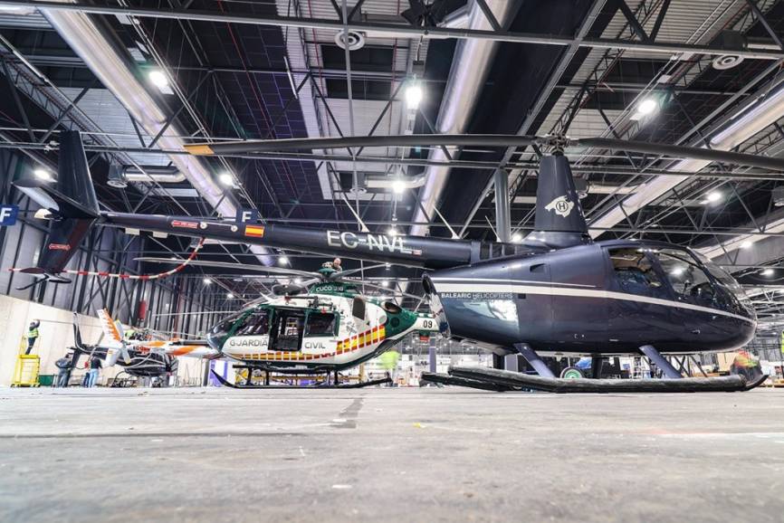 Un Robinson 66 de la empresa Balearic Helicopters en el pabellón 9, detrás se ve el H135 de la Guardia Civil.