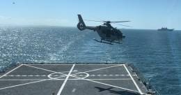 Uno de los nuevos H135 evoluciona sobre la cubierta del Galicia, al fondo se ve el Juan Carlos I. (foto Armada)