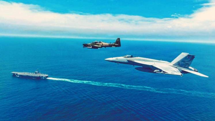 Un avi�n apoyo a�reo Embraer A 29 Super Tucano del Grupo de Caza 23 de la FAE vuela en formaci�n con un caza polivalente Boeing F/A-18E Super Hornet del  VFA 137 �Kestrels", en el fondo el portaaviones USS Nimitz (CVN 68). (Cr�ditos: SOUTHCOM)